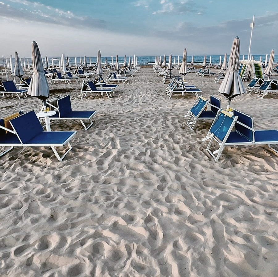 spiaggia deserta con ombrelloni chiusi, cielo pallido